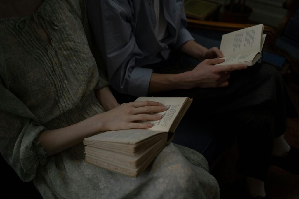 Two individuals reading books together indoors, showcasing leisure and knowledge.